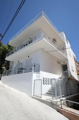 a white building with a balcony on the side of it at Muse Studios & Apartments Aegina in Agia Marina Aegina