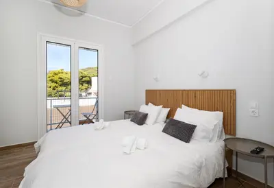 a large white bed in a room with a window at Muse Studios & Apartments Agia Marina in Agia Marina Aegina