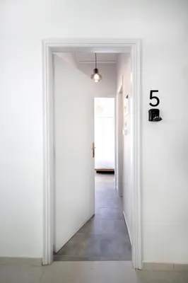 a hallway with a white door with the number at Muse Studios & Apartments Agia Marina in Agia Marina Aegina