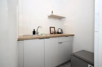 a kitchen with white cabinets and a sink at Muse Studios & Apartments Agia Marina in Agia Marina Aegina