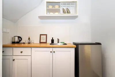 a kitchen counter with a sink and a refrigerator at Muse Studios & Apartments Agia Marina in Agia Marina Aegina