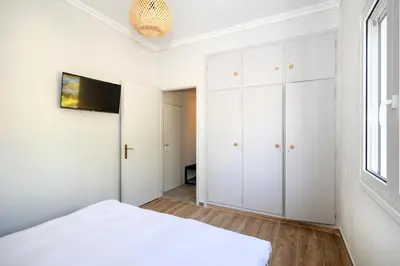 a white bedroom with a bed and a window at Muse Studios & Apartments Escape in Agia Marina Aegina