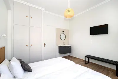 a white bedroom with a bed and a tv at Muse Studios & Apartments Escape in Agia Marina Aegina