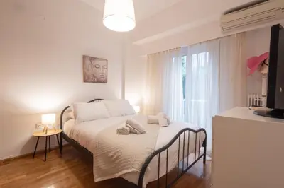 a bedroom with a bed with white sheets and a window at Comfort Apartment with 2 Bedrooms in Athens