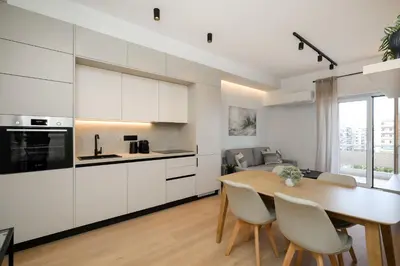 a kitchen and dining room with white cabinets and a table at Piraeus Riviera Residence in Piraeus