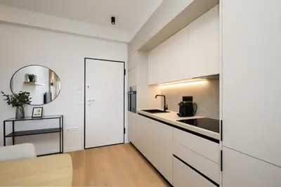 a white kitchen with white cabinets and a table at Piraeus Riviera Residence in Piraeus