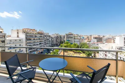 a balcony with chairs and a table and a city at Piraeus Riviera Residence in Piraeus