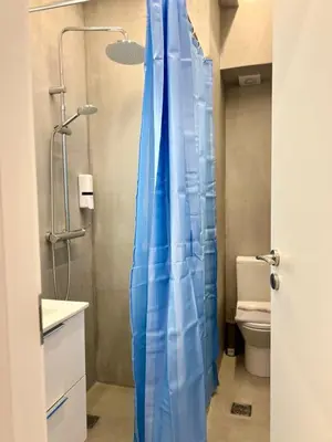 a bathroom with a shower with a blue shower curtain at Family Luxury Suite by Zeus Suites in Athens