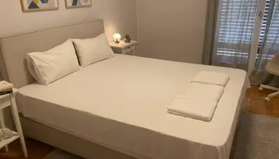 a large white bed with two towels on it at Bright 2-Bedroom Apt in Ampelokipoi Near Hospital in Athens
