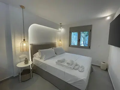 a white bedroom with a bed with two towels on it at Voula Olive Garden by Taurus in Athens