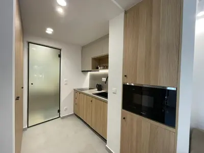 a kitchen with wooden cabinets and a large television at Voula Olive Garden by Taurus in Athens