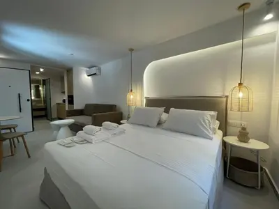 a bedroom with a large white bed and a living room at Voula Olive Garden by Taurus in Athens