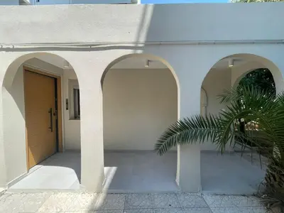 a house with two arched entry doors and a palm tree at Voula Olive Garden by Taurus in Athens