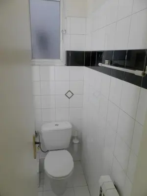 a white bathroom with a toilet and a window at Comfortable apartment by the Metro in Athens