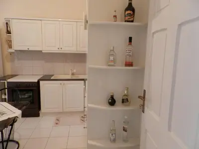 a kitchen with white cabinets and bottles on shelves at Comfortable apartment by the Metro in Athens