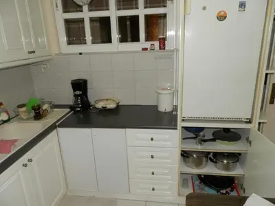 a kitchen with white cabinets and a black counter top at Comfortable apartment by the Metro in Athens