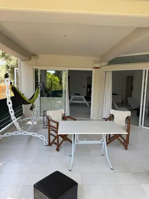a porch with a hammock and a table and chairs at Oasis 3 minutes from the beach in Vari