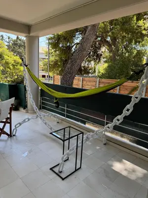 a hammock on a porch with a tree at Oasis 3 minutes from the beach in Vari