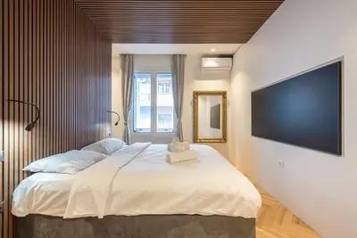 a bedroom with a large bed with a flat screen tv at Modern 1BR in Exarchia l Green-View Balcony in Athens