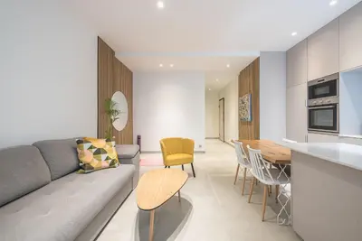 a living room with a gray couch and a kitchen at Modern 1BR in Exarchia l Green-View Balcony in Athens