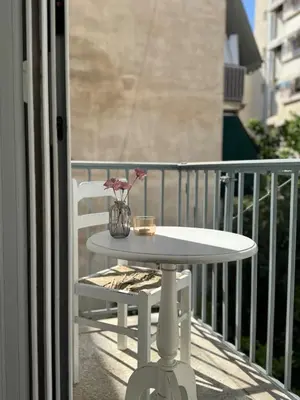 a white table and a chair on a balcony at Arisa Apartment in Athens next to Metro Station in Athens