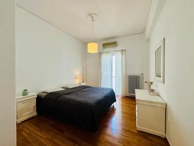a bedroom with a black bed and a wooden floor at Arisa Apartment in Athens next to Metro Station in Athens
