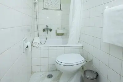 a white bathroom with a toilet and a bath tub at Cozy Minimal Studio by Ampelokipoi Metro in Athens