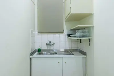 a small kitchen with a sink and white cabinets at Cozy Minimal Studio by Ampelokipoi Metro in Athens