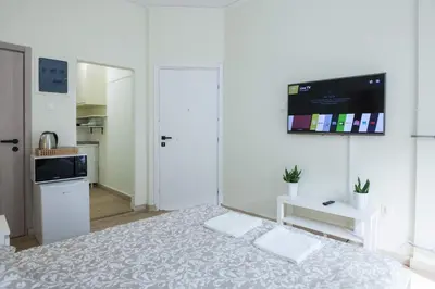 a white bedroom with a bed and a tv on the wall at Cozy Minimal Studio by Ampelokipoi Metro in Athens