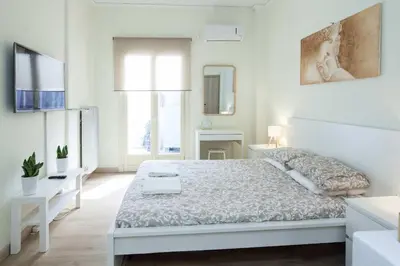 a white bedroom with a white bed and a window at Cozy Minimal Studio by Ampelokipoi Metro in Athens
