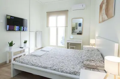 a white bedroom with a bed and a mirror at Cozy Minimal Studio by Ampelokipoi Metro in Athens