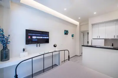 a kitchen with white cabinets and a tv on the wall at Stylish Apartment-Κέντρο Αθήνα-15' περπάτημα από την Ακρόπολη in Athens