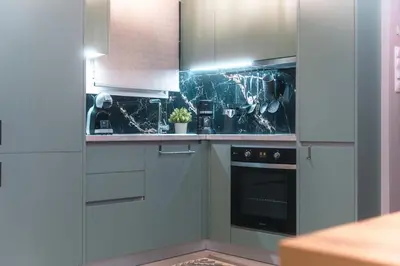 a kitchen with white cabinets and a black oven at Lovely Goudi Apartment - Perfect Athens Getaway in Athens