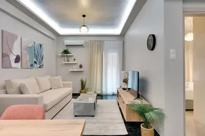 a living room with a white couch and a tv at Lovely Goudi Apartment - Perfect Athens Getaway in Athens