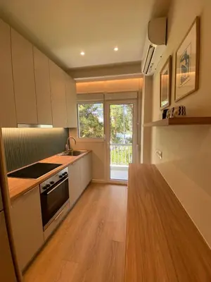 a kitchen with white cabinets and a wooden counter top at Chic Athenian Apartment by the Riviera in Athens