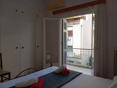 a bedroom with a bed with a view of a balcony at Quiet private room in a dormitory 5' from metro in Athens
