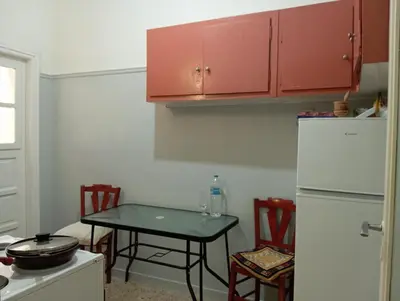 a kitchen with a table and a white refrigerator at Quiet private room in a dormitory 5' from metro in Athens
