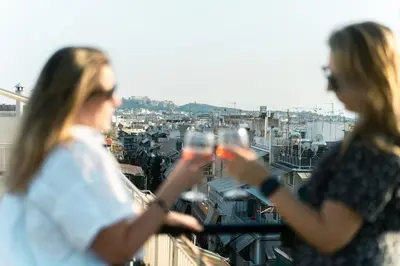 two women standing on a balcony holding wine glasses at Skyline Spa Athens 130 A in Athens