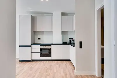 a kitchen with white cabinets and a wooden floor at Skyline Spa Athens 130 A in Athens