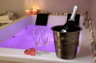 a bucket of champagne and two wine glasses in a bathtub at VIP Suite 108 - Castle De Paris in Athens