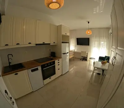 a kitchen with white cabinets and a table and a dining room at Little Big Athens in Athens