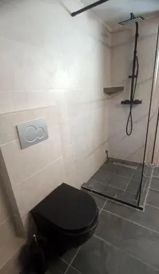 a bathroom with a black toilet and a shower at Spacious house by the sea in Athens