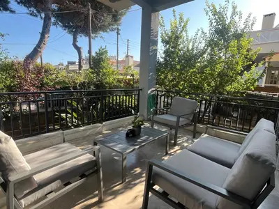 a patio with chairs and tables on a balcony at Spacious house by the sea in Athens
