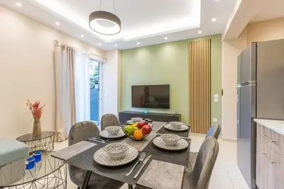 a dining room with a table and chairs and a television at Saronic retreat Varkiza in Vari