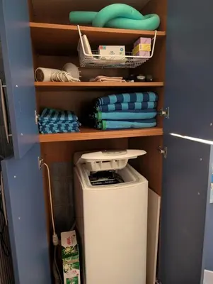 a small closet with a washing machine and towels at Family apartment mountain and sea in Athens
