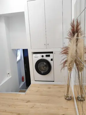 a laundry room with a washing machine in a white cabinet at LD Homes 1 in Athens
