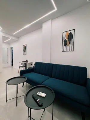 a living room with a blue couch and two tables at Apollon Residence Patision by Zeussuites in Athens
