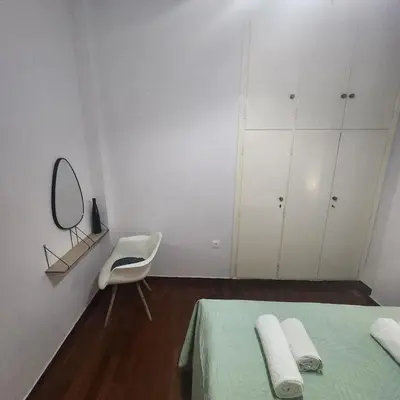 a bedroom with a bed and a chair and white cabinets at Athens Acropolis in Athens