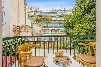 a balcony with tables and chairs and a view of buildings at Salver Stays in Athens