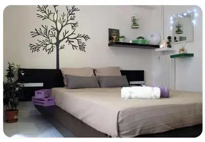a bedroom with a large bed with a tree on the wall at Cute apartment Center of Athens Petralona station in Athens